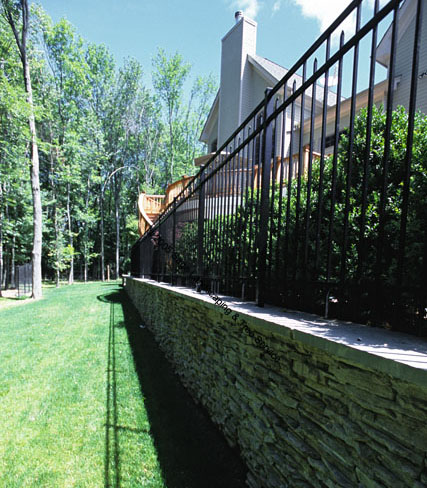 Stone Retaining Wall with Aluminum Fence and Shrubs